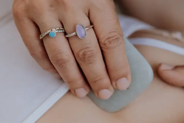A-hand-with-rings-glides-a-jade-stone-over-smooth-skin-suggesting-a-soothing-massage-or-therapeutic-treatments